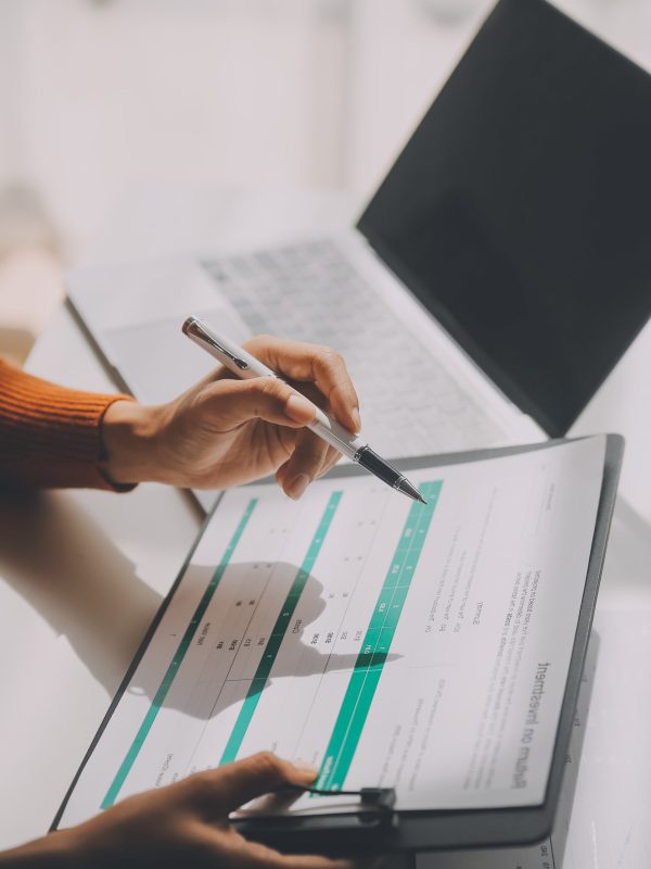 Asian Businesswoman Using laptop computer and working at office with calculator document on desk, doing planning analyzing the financial report, business plan investment, finance analysis concept.